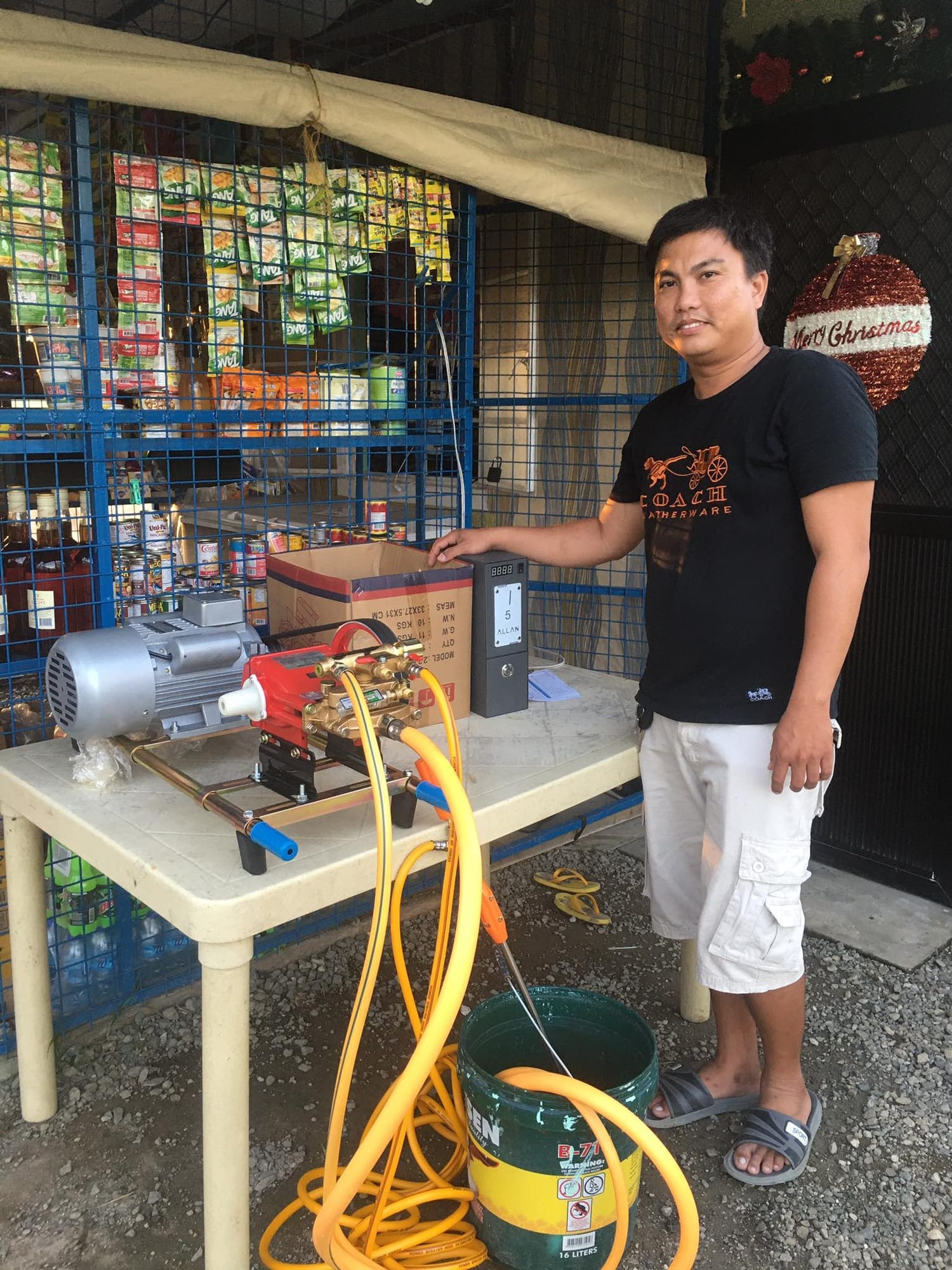A MyLoad N Wash unit assembled on a table outside a neighborhood store, its operator beside it