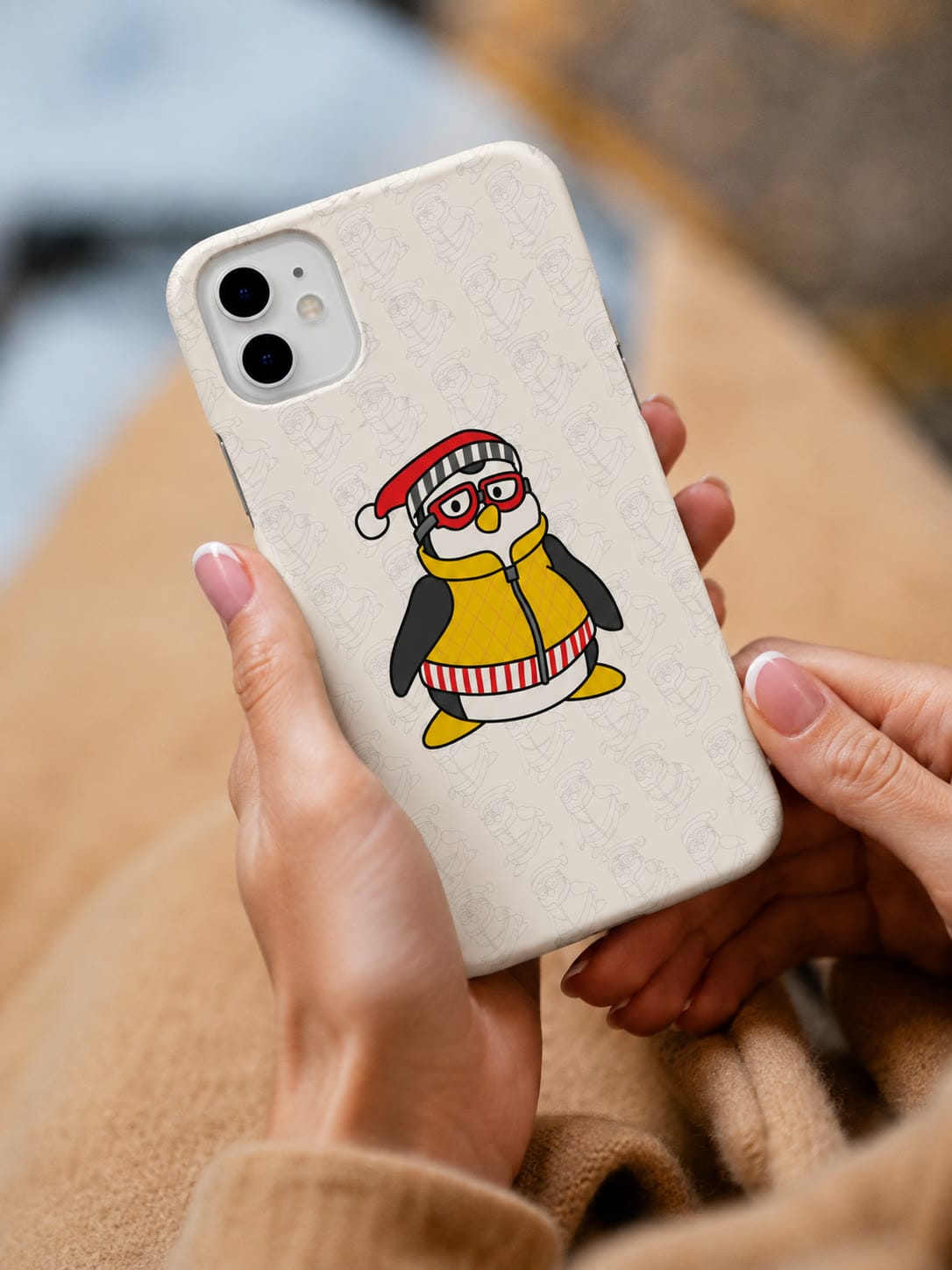 Hands holding a cream Our Case phone case printed with a scarfed penguin