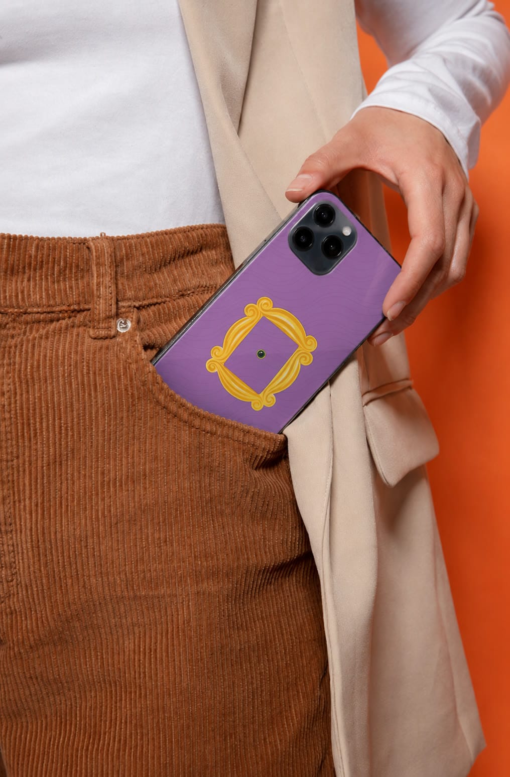A purple Our Case phone case in the pocket of rust corduroy trousers