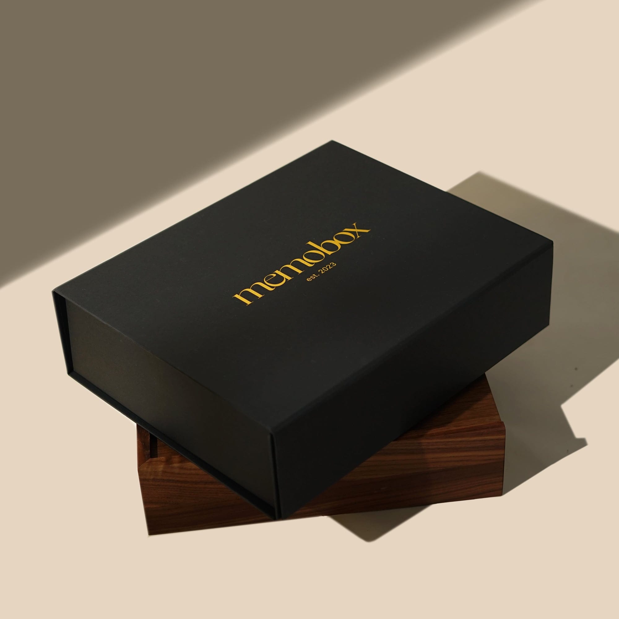 The closed black Memobox stacked on its walnut base in hard light