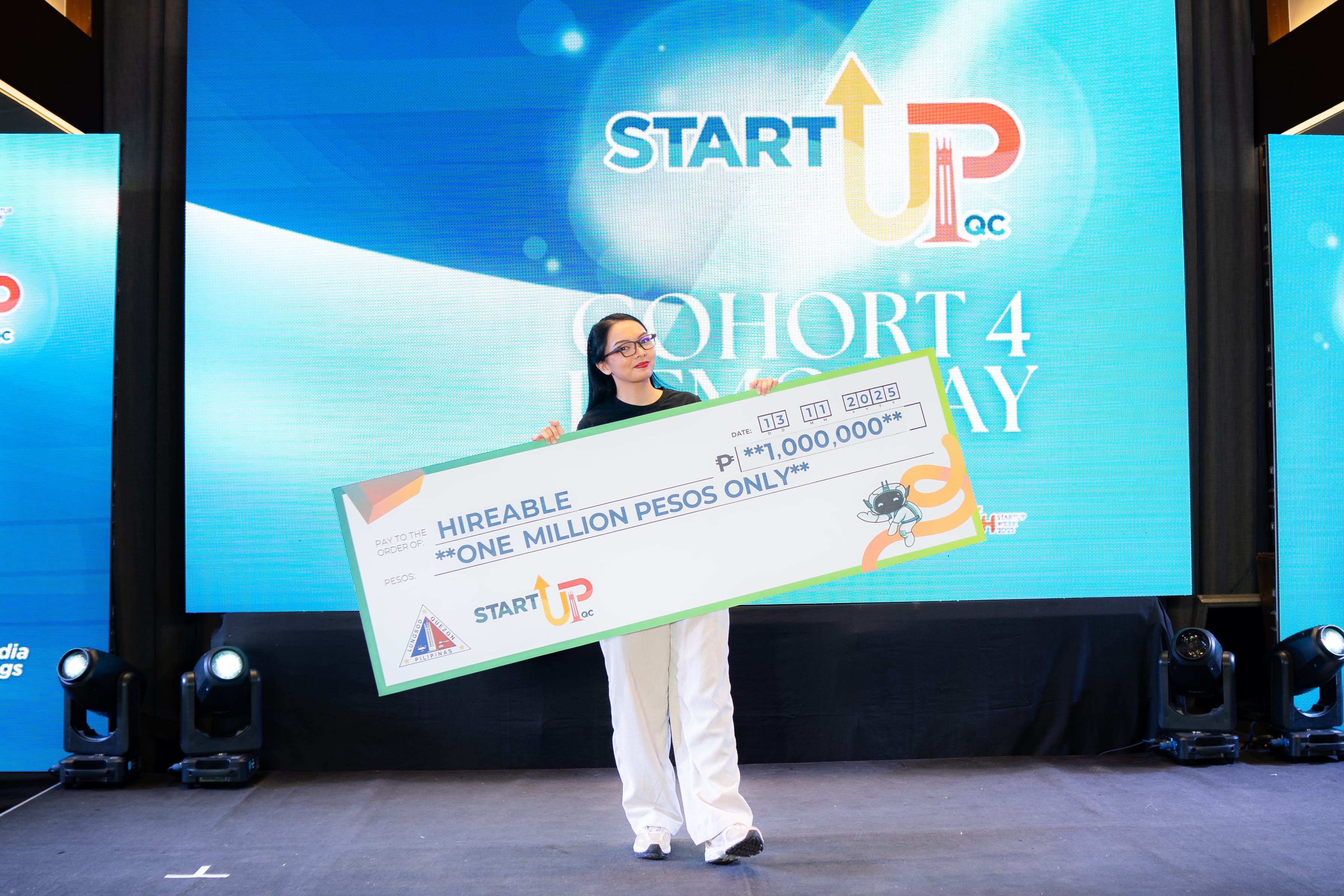 Holding the ₱1,000,000 cheque on the Startup QC Cohort 4 Demo Day stage